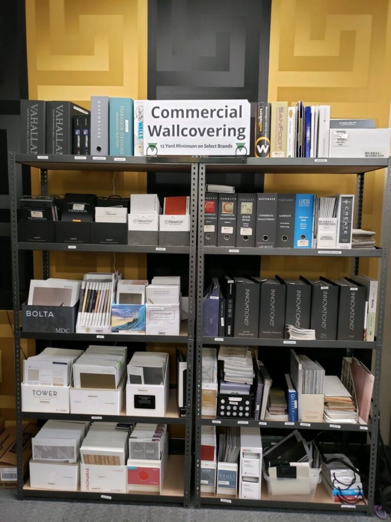 A shelf displaying various commercial wallcovering samples, with a sign reading "Commercial Wallcovering" at the top.