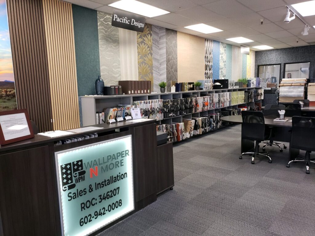 Interior of a wallpaper and design store with a reception desk, sample displays on walls, catalog racks, and a conference table.